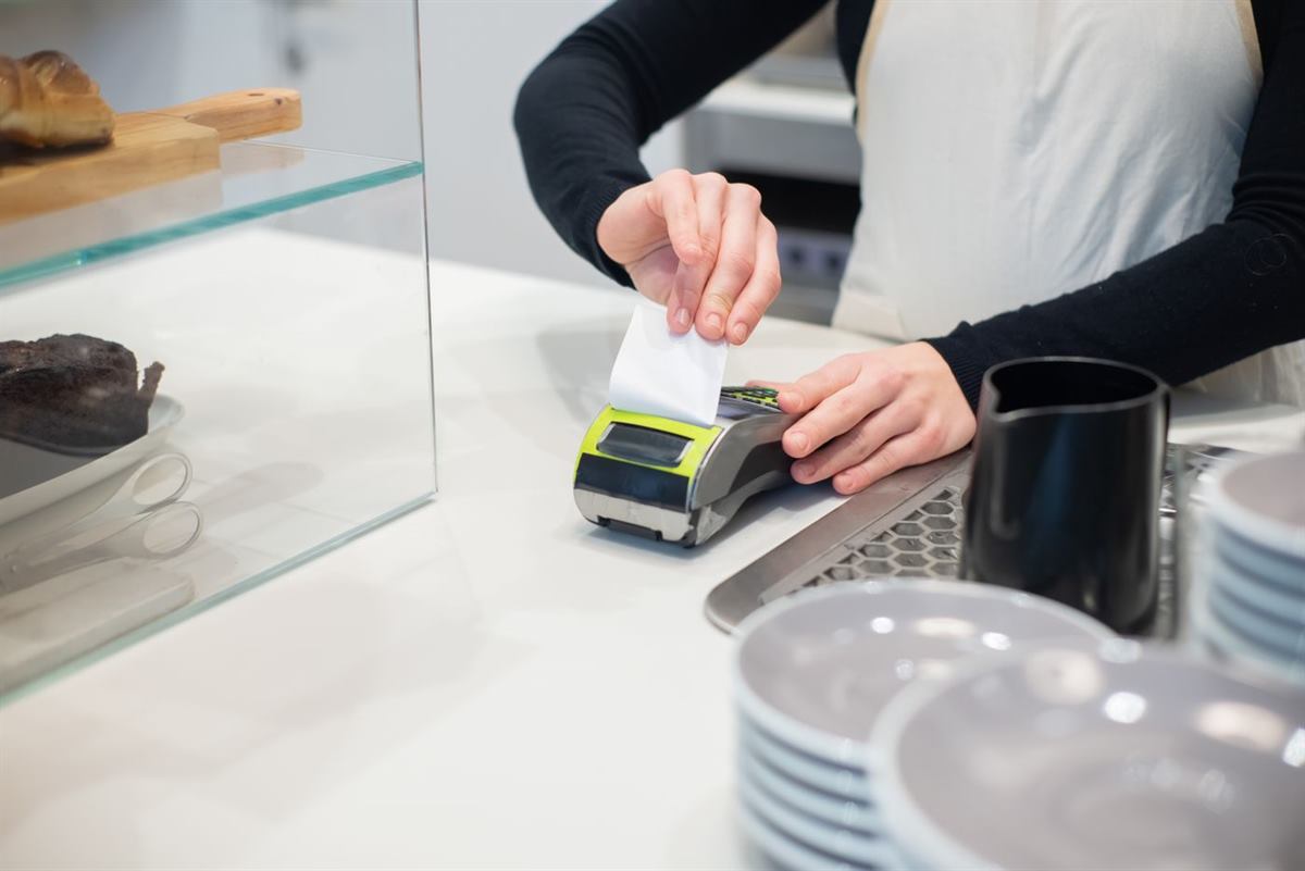 A café worker taking a payment at a countertop terminal