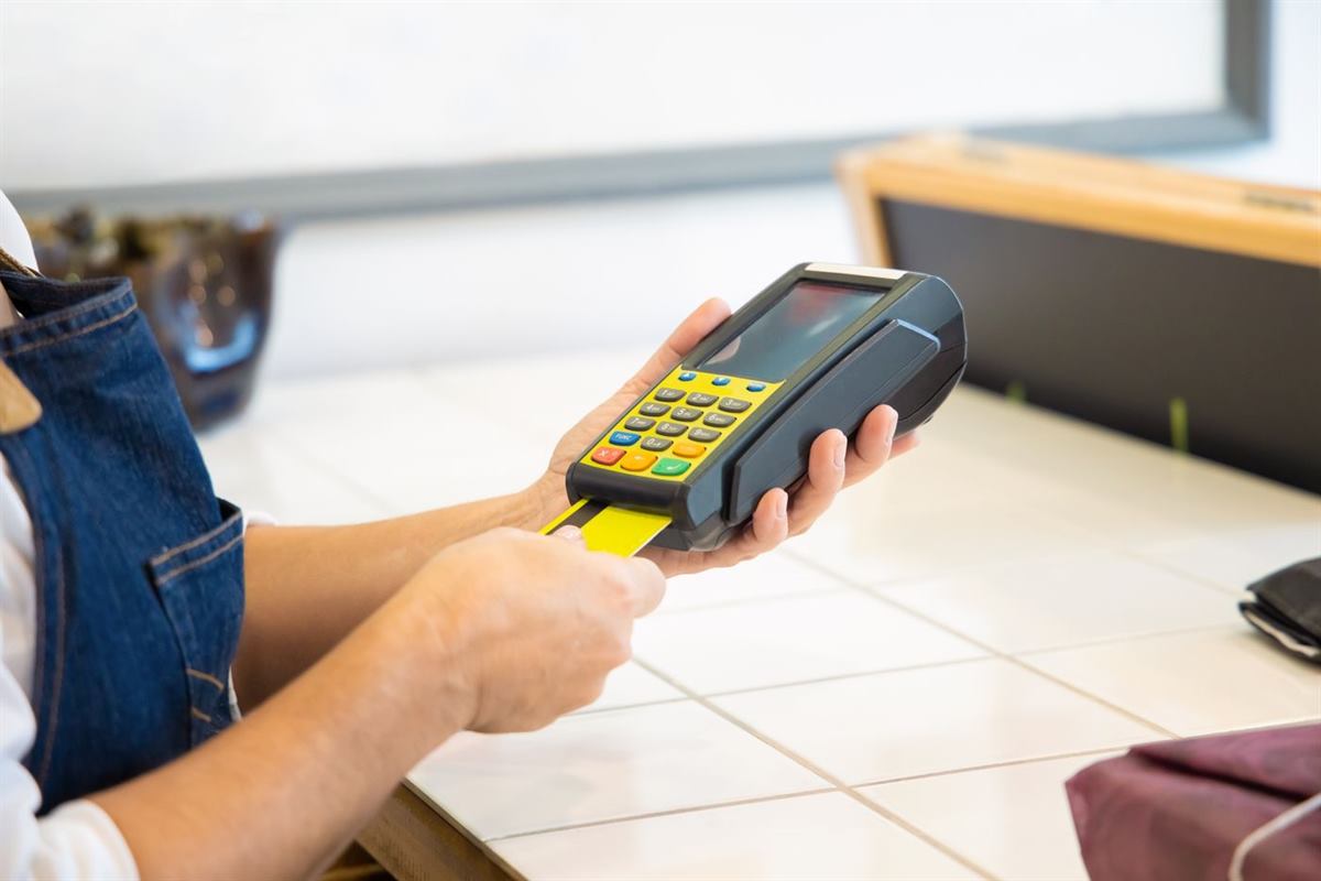 A shopkeeper holding a card terminal while a customer pays