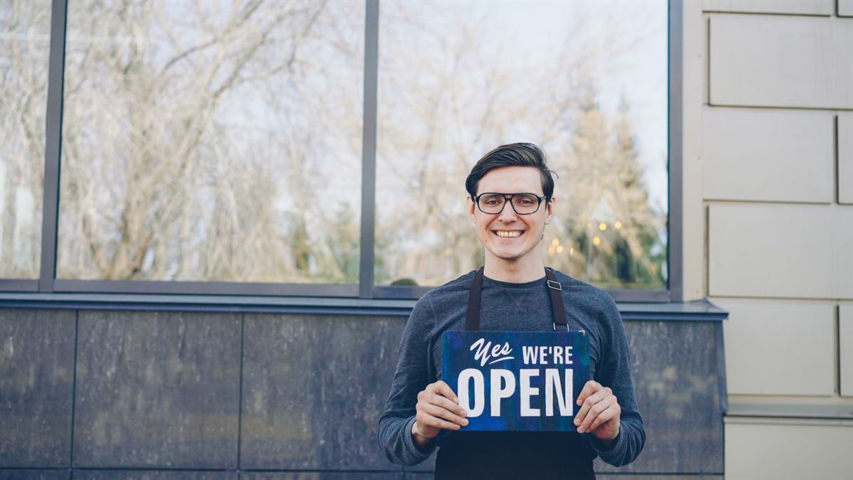 A shop owner holding an open sign outside their business