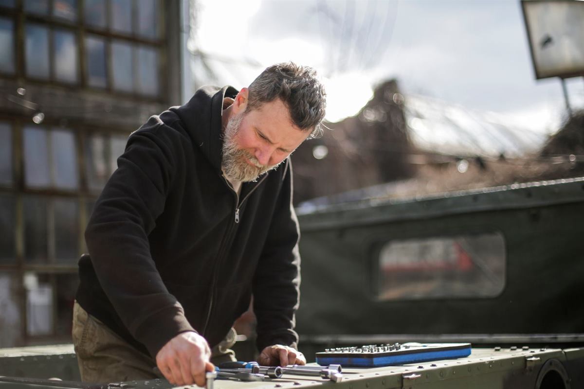A tradesperson working on a vehicle in a workshop